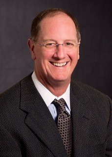 photo of Chad Stearns, a middle aged white man wearing glasses and a dark suit