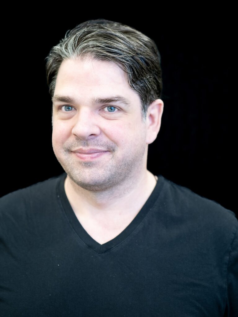 Photo of Kris Vandecruys, a white man with dark hair, wearing a black t-shirt.